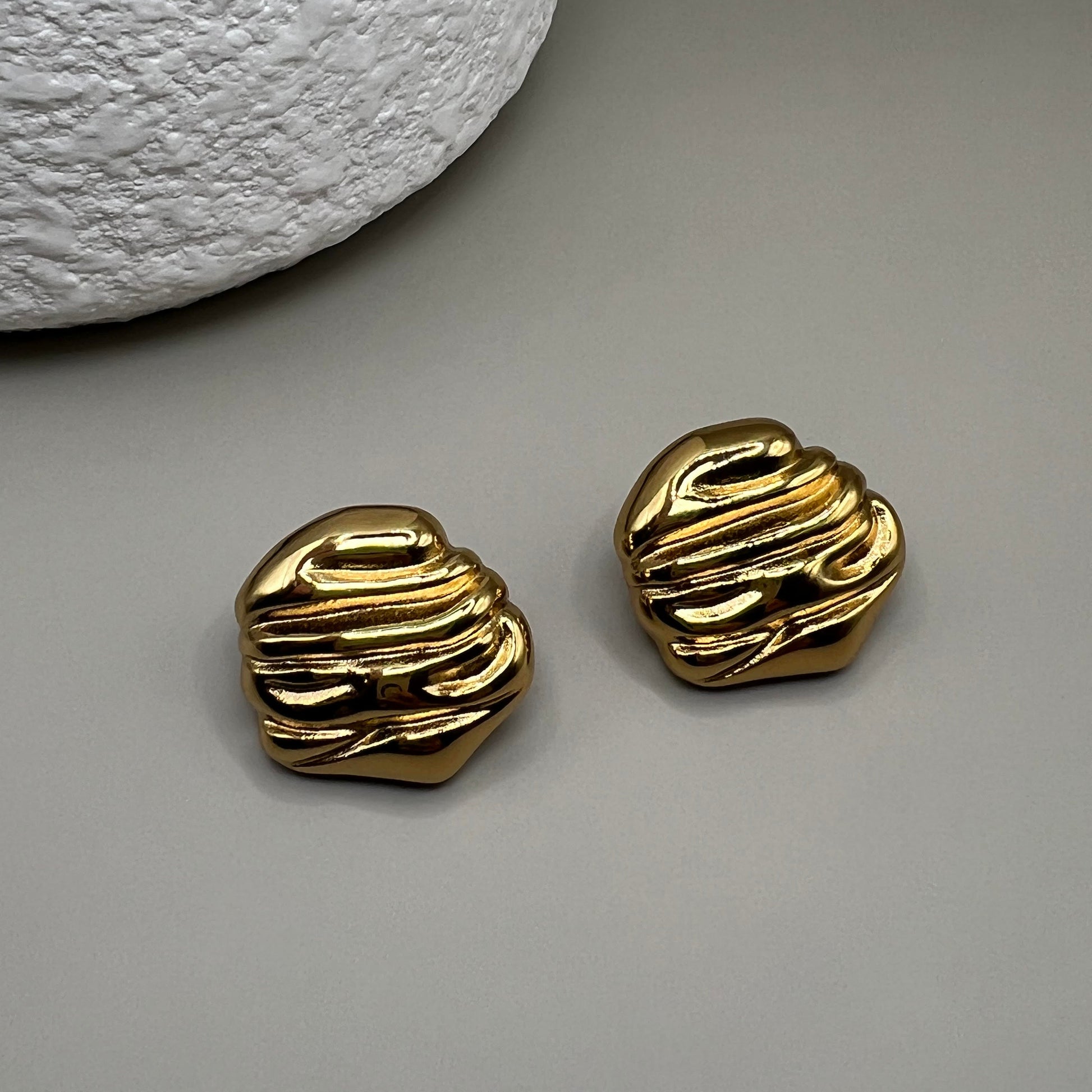 This image displays a pair of elegant "Juliet Earrings" with a striking gold finish. The earrings are crafted in a unique, textured design that resembles a braided or twisted pattern, adding a touch of modern sophistication.