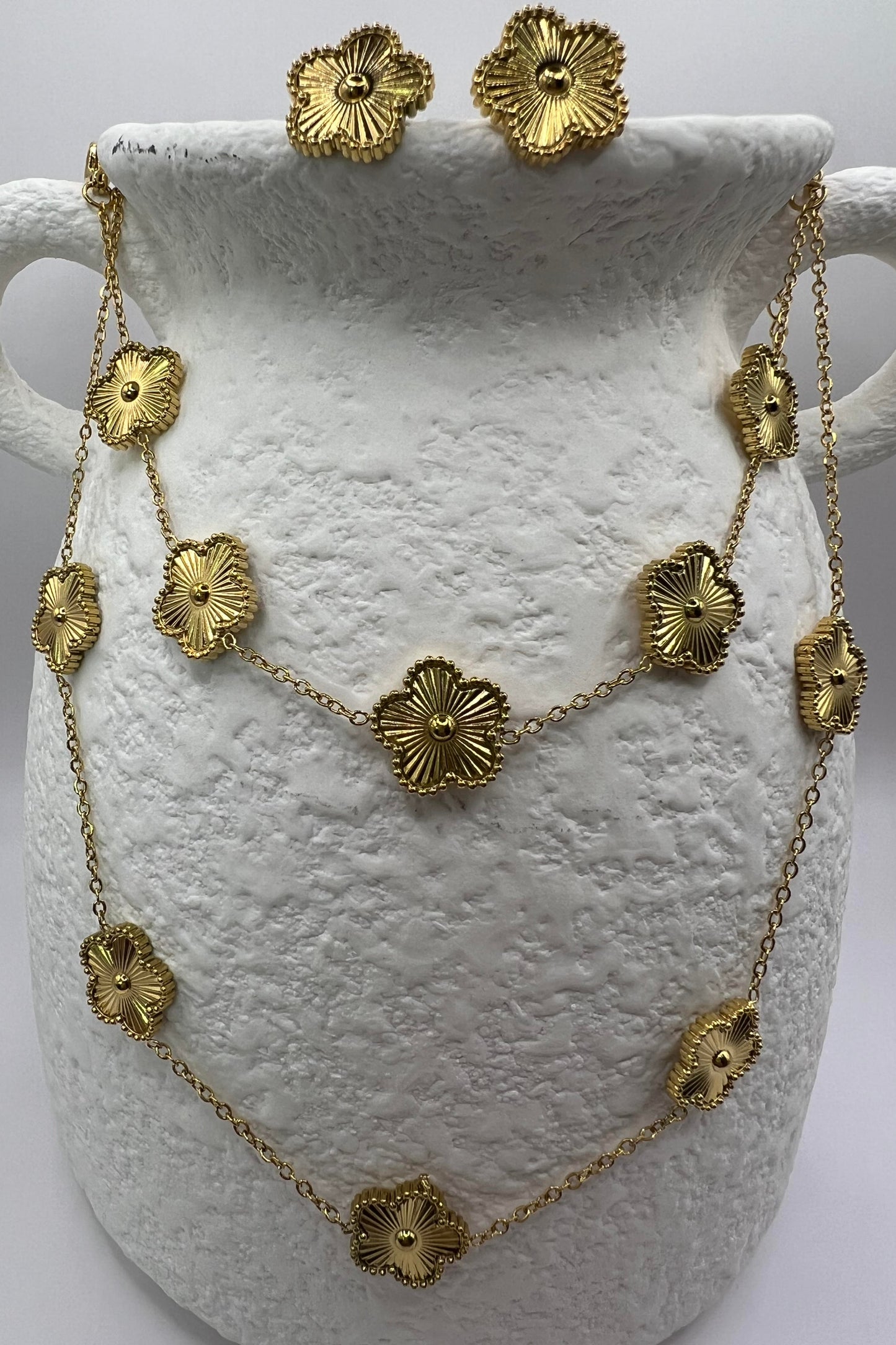Gold necklace and earrings on a white vase