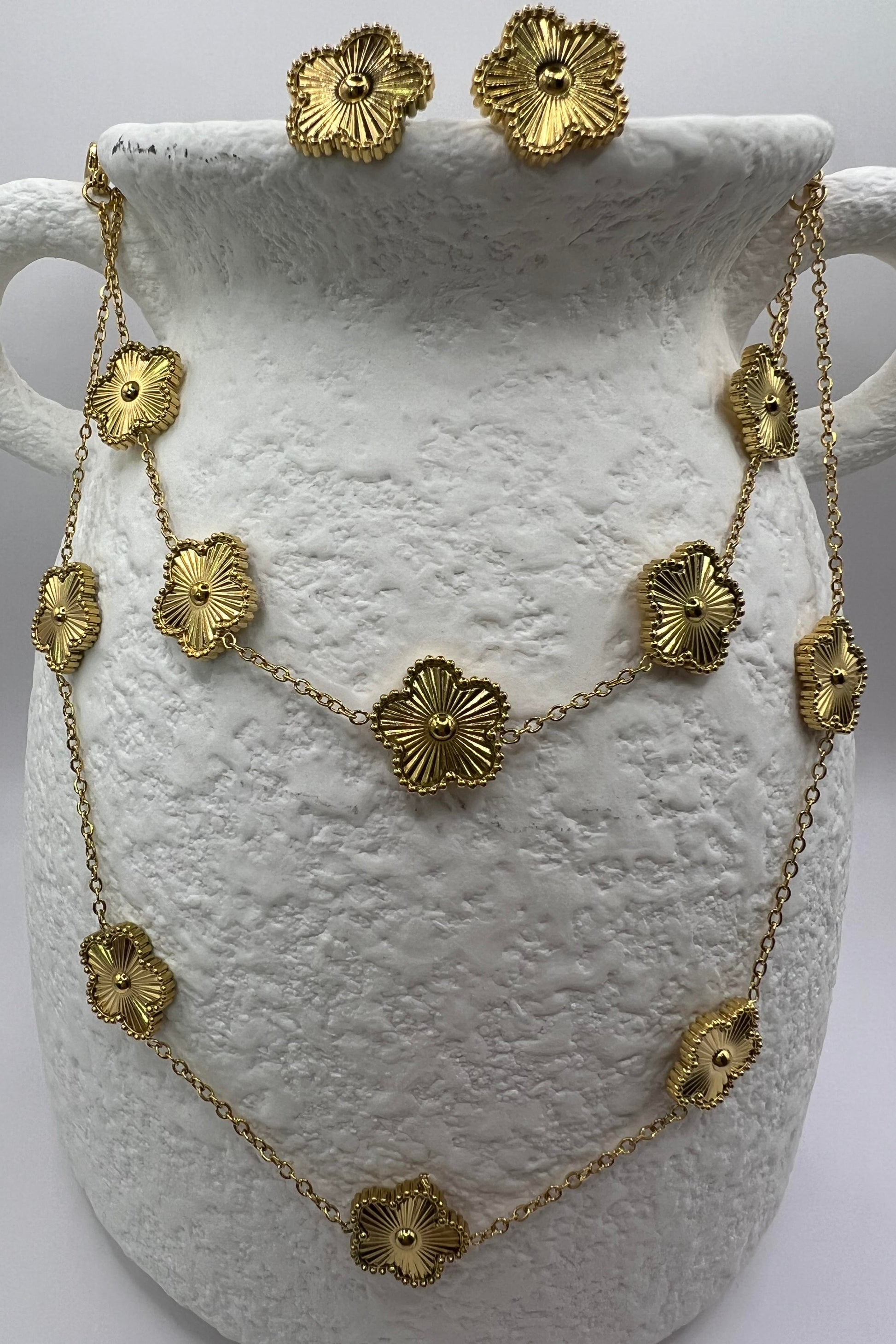 Gold necklace and earrings on a white vase