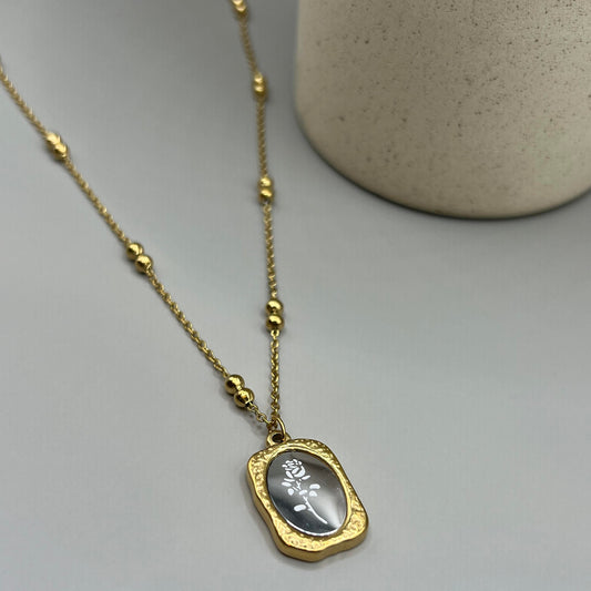 A gold-colored necklace with a lobster clasp closure, featuring a central pendant depicting a rose.